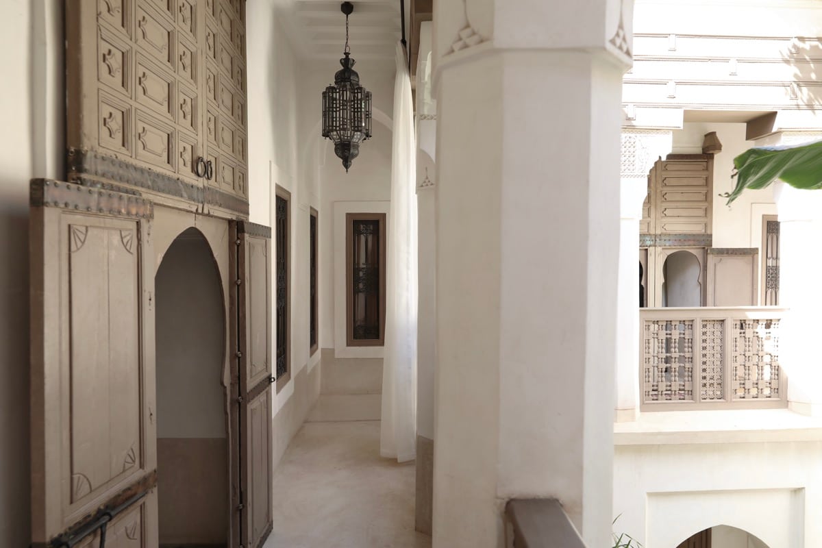 Plâtre sculpté, portes en cèdre et colonnes blanches le long de la galerie