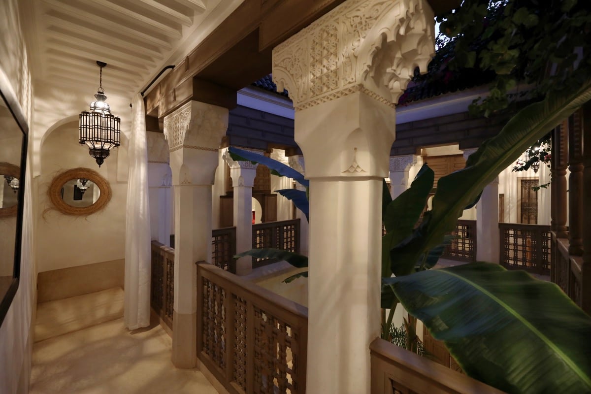 Une galerie haute sculptée ouverte sur le patio au crépuscule